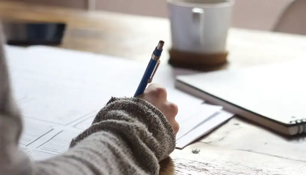Personne dessinant les wireframes d’un site internet sur papier